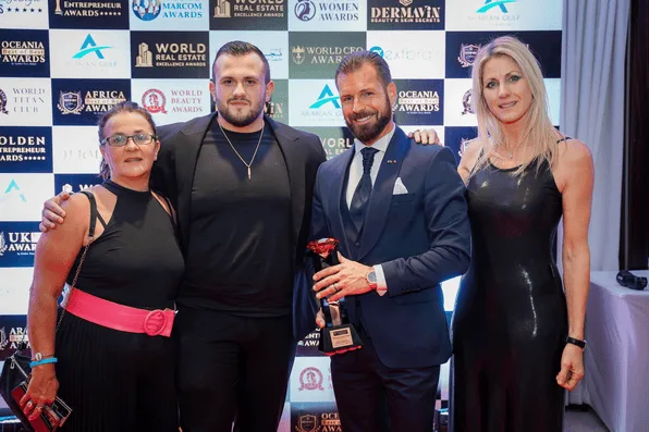 Group of four posing with an award trophy at the Hospitality Awards gala step-and-repeat wall